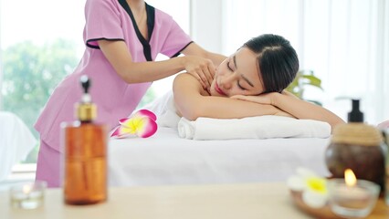 Obraz na płótnie Canvas Healthy and beautiful Asian woman in white towel lying on spa bed closed eyes relaxing receiving neck and shoulders massage. Spa treatment concept