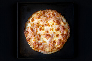 Pizza rotonda con pomodoro e mozzarella in primo piano su sfondo nero