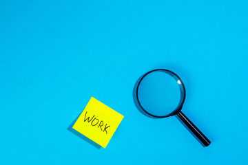 Magnifying loupe and a sticker with the word work on a blue background.