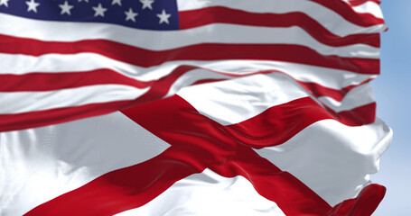 The flag of the state of Alabama waving alongside the national flag of the United States on a sunny day