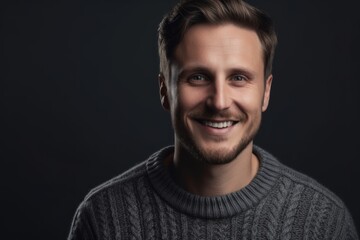 Fototapeta premium Portrait of a handsome young man in a gray sweater on a black background