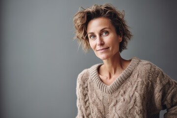 Portrait of a beautiful woman with curly hair in a sweater on a gray background