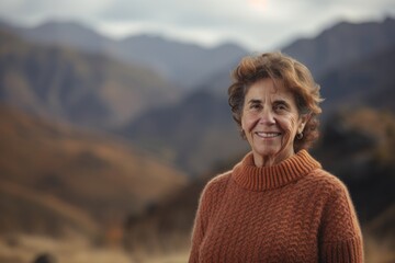 Naklejka premium Portrait of a smiling senior woman in a sweater in the mountains