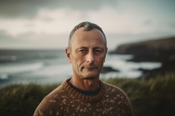 Portrait of handsome senior man standing on the beach with ocean in background