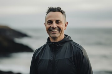 Portrait of a smiling sporty man standing on the beach and looking at camera