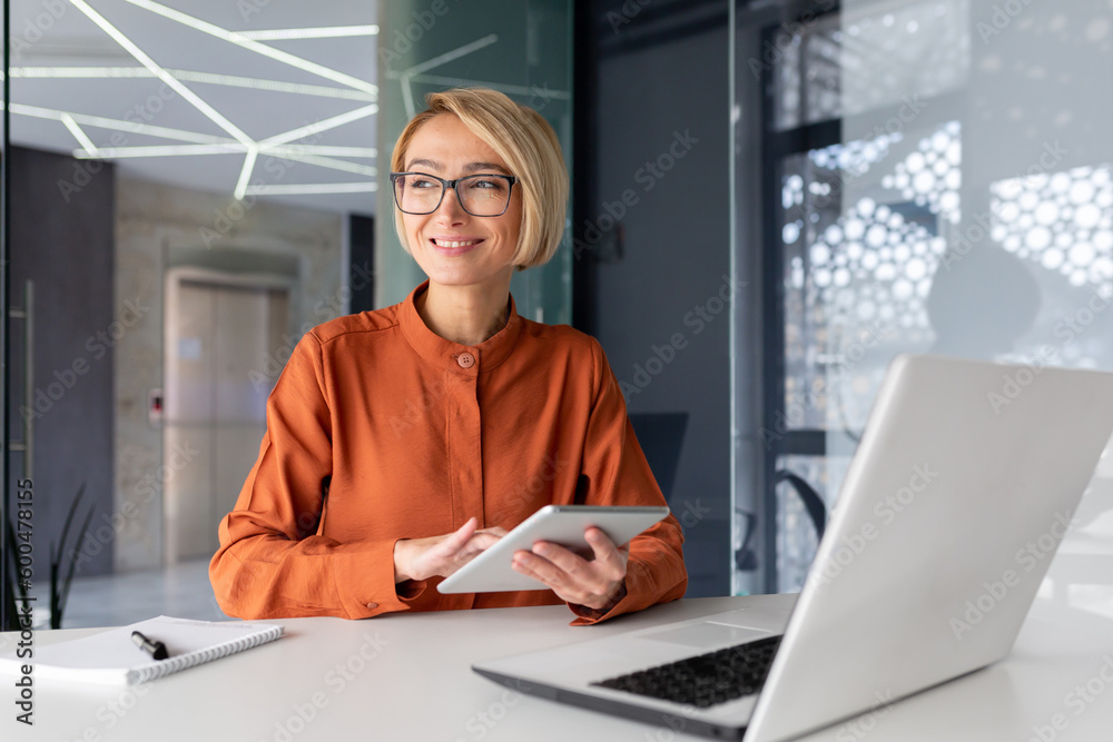 Wall mural young successful businesswoman at workplace is satisfied with results of achievement at work smiling