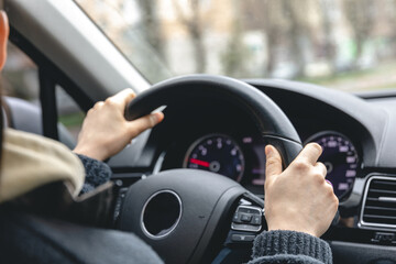 Woman driver's hands on a car steering wheel.