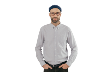 Indoor shot of satisfied Caucasian man in spectacles with bristle, keeps hands in pockets, dressed in formal stylish clothes, has gentle smile, happy to be promoted, isolated over white background.