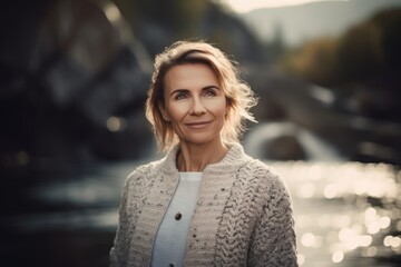 Fototapeta premium Portrait of a beautiful middle-aged woman in a knitted sweater on the background of the river