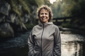 Portrait of senior woman in sportswear standing near river.