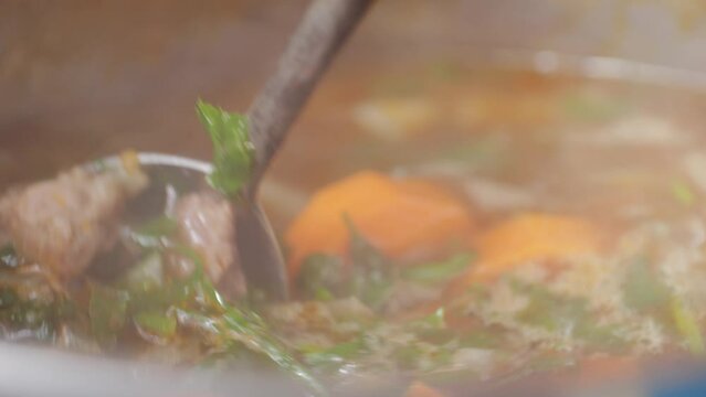 Hungarian goulash soup cooking close-up in pot, chef cook traditional polish or zech soup in restaurant. 