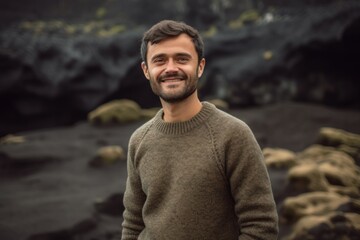 Portrait of a handsome young man smiling at the camera while standing in front of a volcanic landscape