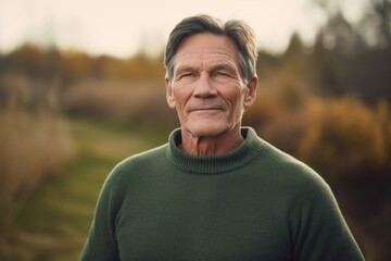 Portrait of a handsome senior man in a green sweater on a blurred background.
