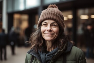 Fototapeta premium Portrait of smiling middle-aged woman in a hat and coat in the city