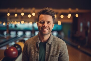 Fototapeta premium Portrait of happy young man in bowling alley at night. Smiling man looking at camera.