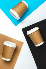 Paper cups on colored paper background, top view.