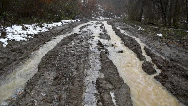 Muddy water flow down the dirt road like stream, wheel rut full of water