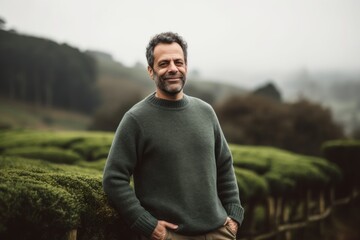 Portrait of a handsome man standing in a tea plantation on a foggy day