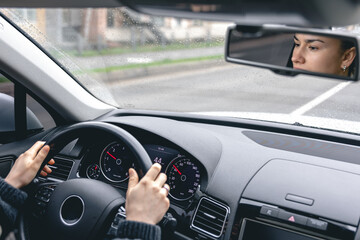 Fototapeta premium Woman drive a car reflects in back view mirror.