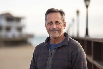 Fototapeta premium Portrait of handsome mature man with grey hair smiling at camera on the beach