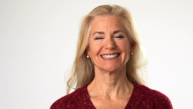 Closeup portrait of happy smiling beautiful 50s middle aged mature woman looking at camera, laughing on white background. Anti age face beauty, skin and body care, wellness and self care concept
