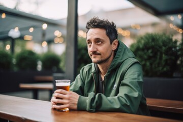 young man drinking beer at bar counter in bar or pub outdoors.