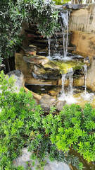Green Nature Garden decoration of Mini waterfall set with stone and tropical fern plant forest patterns in the garden 