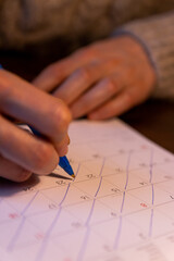 A person holding a pen crossing days of the month off of a calendar. Passing of time concept