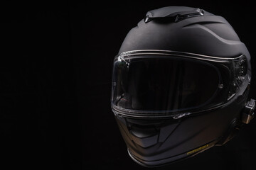 Black motorcycle helmet on dark background, space for text 