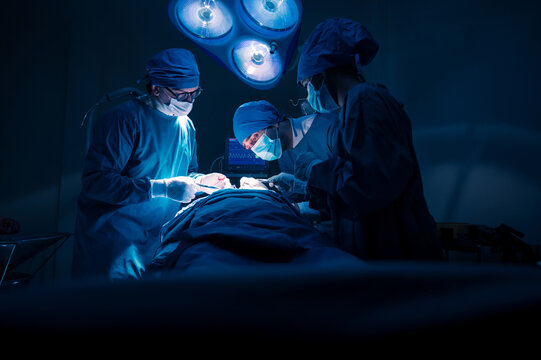 Group of concentrated surgical doctor team doing surgery patients in hospital operating theater. Professional medical team doing critical operations.