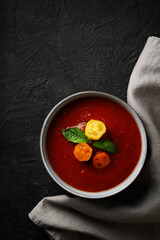 Gazpacho soup with tomato and ingredients on black background