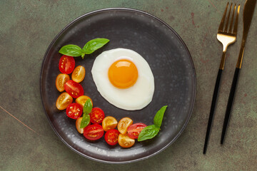 Fried eggs and Caprese salad with tomatoes, mozzarella cheese and basil leaves in a plate. Top view.