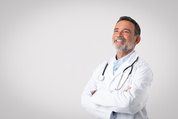 Smiling european senior man doctor in white coat with a stethoscope with crossed arms on chest, enjoy work