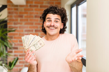 young handsome man with dollar banknotes at home interior