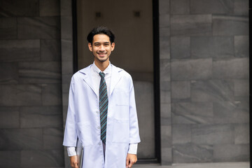 Cheerful Asian young man doctor posing and smiling looking at camera. healthcare and medicine