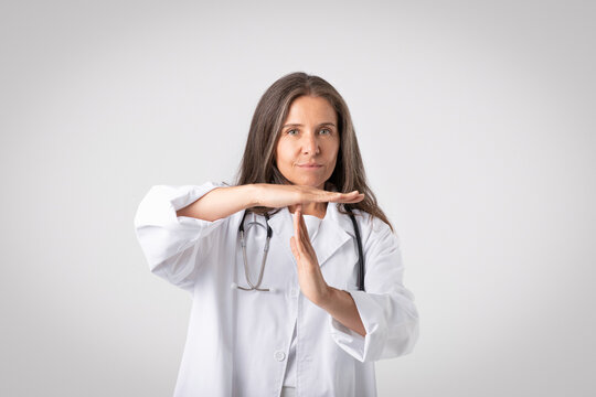 Senior doctor woman demonstrating time out gesture, highlighting the significance of self-care and work-life balance