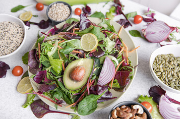Salad of avocado and vegetables mixed greens lettuce leaves ready to eat.