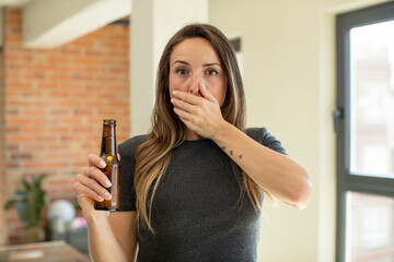 pretty woman covering mouth with a hand and shocked or surprised expression. beer bottle