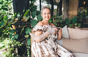 Smiling woman sitting with coffee cup on sofa