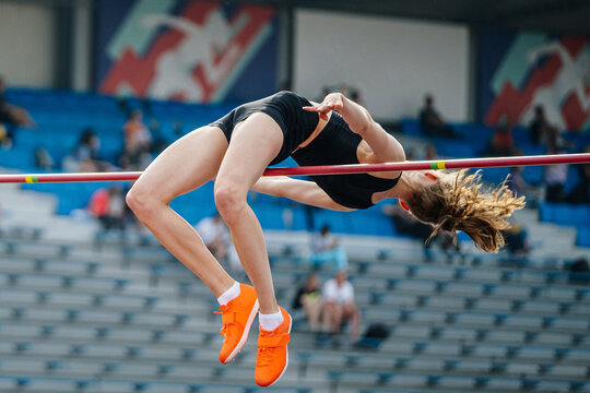 young woman jumper high jump in summer athletics championships, fosbury flop technique