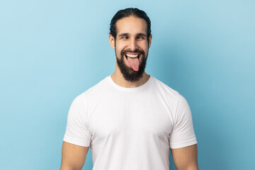 Portrait of comic positive man with beard wearing white T-shirt looking cross-eyed, having fun with...