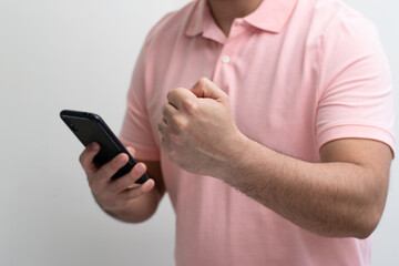 Close up of mid body of man cheering with strong hands while look their cell phone in white background