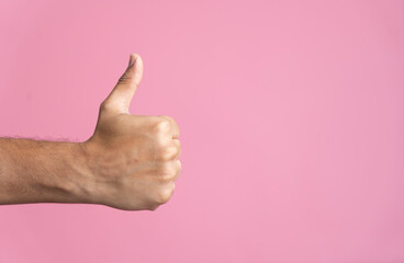 Male hand with thumb up isolated on pink background with copy space