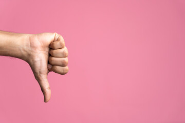 Thumb down male hand  isolated on pink background, dislike concept image