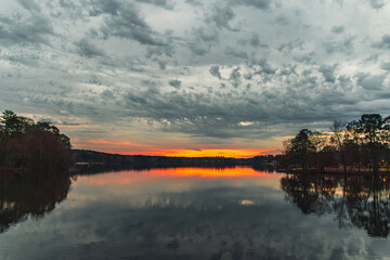 beautiful sunset with the reflection of the forest trees in the lake