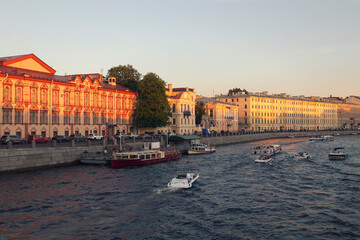 Naklejka premium A view from a river on quay, motorboats and historical facades of Saint Petersburg against clear blue sky by a warm summer evening.