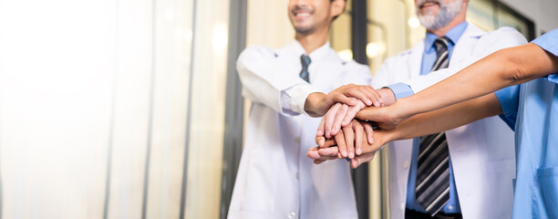 Diverse doctor and nurse stack hands together at hospital medical wellness center. Professional medical staff people successful and teamwork concept