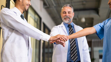 Diverse doctor and nurse stack hands together at hospital medical wellness center. Professional medical staff people successful and teamwork concept