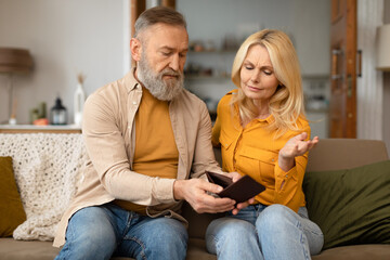 Unhappy Senior Couple Looking At Empty Wallet Sitting At Home