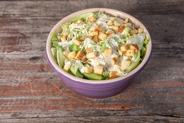 Delicious caesar salad in bowl on wooden background